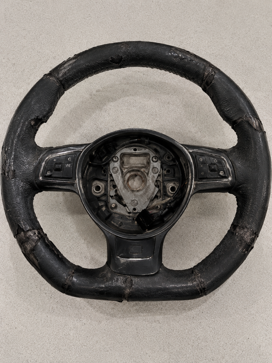 Worn and shiny Audi R8 flat-bottom steering wheel before custom leather restoration.