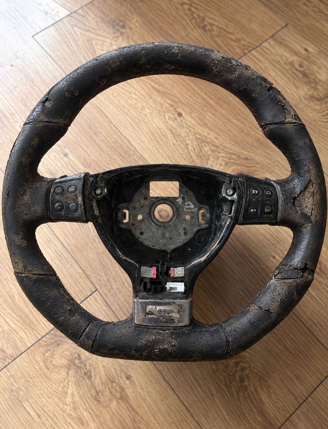 Shiny, greasy, and worn Volkswagen Golf R leather steering wheel before detailing.